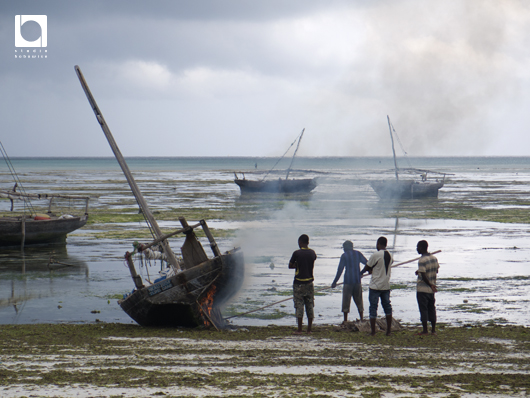 ヌングイのビーチで漁船に火を当てる人たち